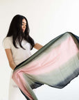 Iris Kiwi Green Pink Cashmere Merino Handwoven Scarf held by a model, showcasing its unique blend of colors and luxury.