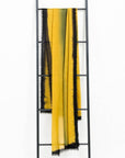 Iris Topaz Yellow Olive Green Cashmere Merino Soft Handwoven Modern Artisanal Scarf displayed on a ladder.