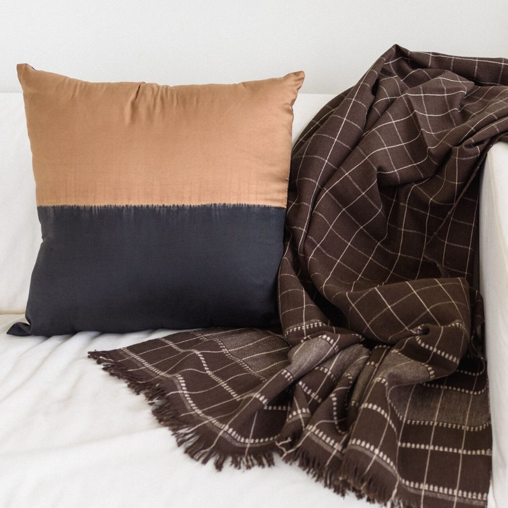 Kala Black & Gold Color Block Mulberry Silk Square Pillow with a brown and black woven throw blanket.
