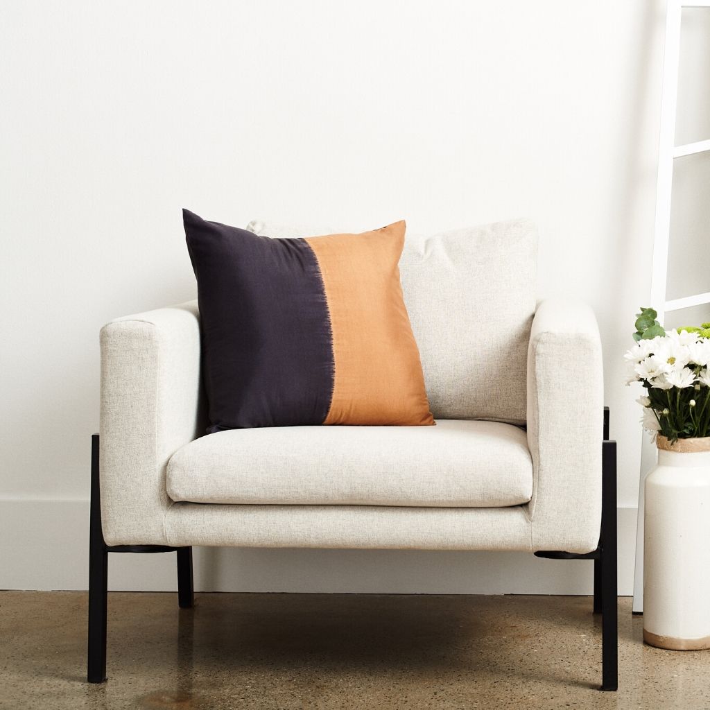 Kala Black & Gold Color Block Mulberry Silk Square Pillow on a cozy chair.