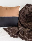 Kala Black & Gold Color Block Mulberry Silk Square Pillow with a brown and black woven throw blanket.