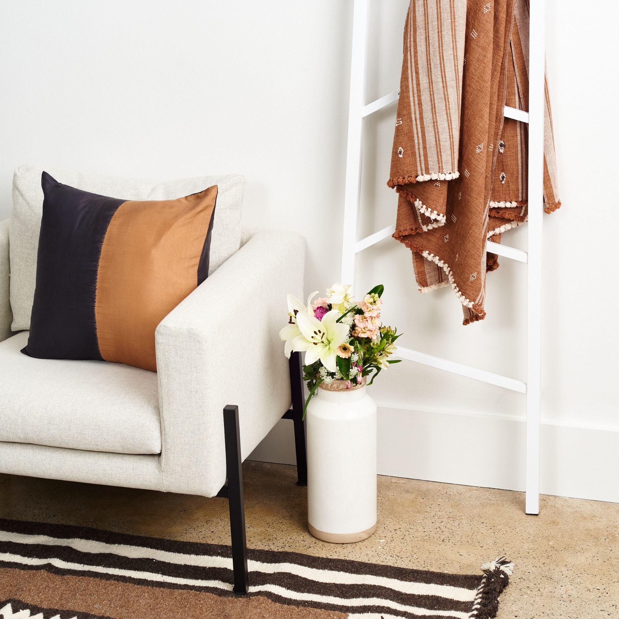 Kala Black & Gold Color Block Mulberry Silk Square Pillow on a stylish sofa with flowers and a cozy throw.
