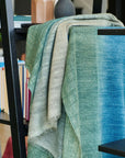 Lake Moss Handwoven Merino Throw Blanket draped over a shelf, showcasing serene blue and green shades.