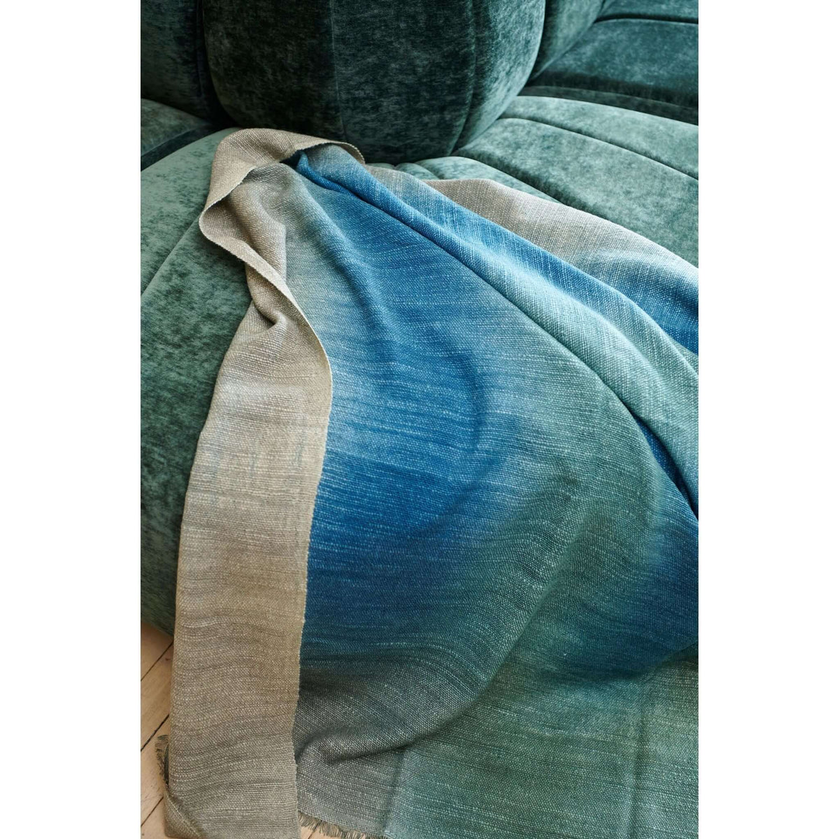 Lake Moss Handwoven Merino Throw Blanket showcasing serene blue-green shades on a plush couch, ideal for cozy decor.