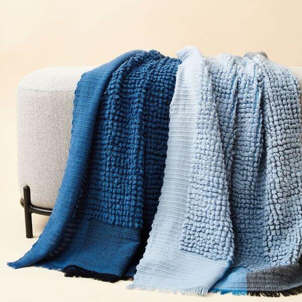 Macaroon Midnight Dark Blue Textured Merino Handloom Throw draped elegantly over a light-colored couch.