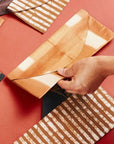 Melo Gold Mulberry Silk Shibori Hand Crafted Envelope Pouch being held, showcasing its unique design and artisan craftsmanship.