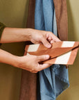 Person holding the Melo Gold Mulberry Silk Shibori Hand Crafted Envelope Pouch with a soft fabric backdrop.