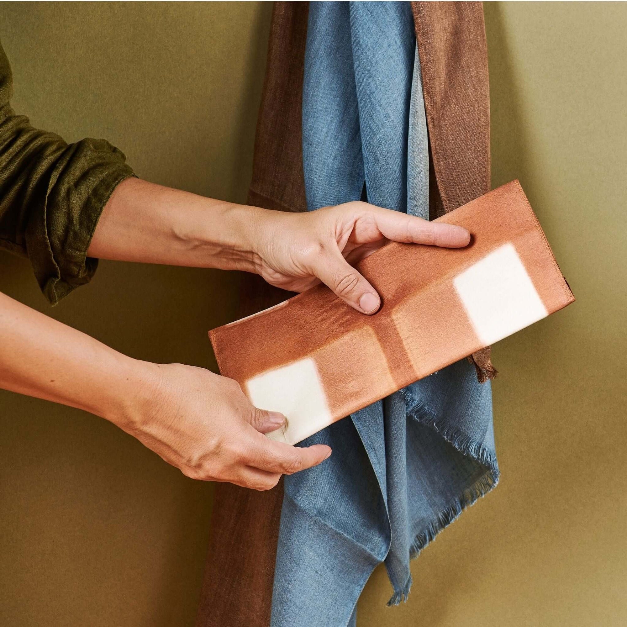 Melo Gold Mulberry Silk Shibori Hand Crafted Envelope Pouch being held by a person, showcasing its unique design.