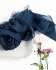 Midnight Navy Blue Hand Woven Linen Silk Blend Scarf elegantly displayed in a bowl with flowers.
