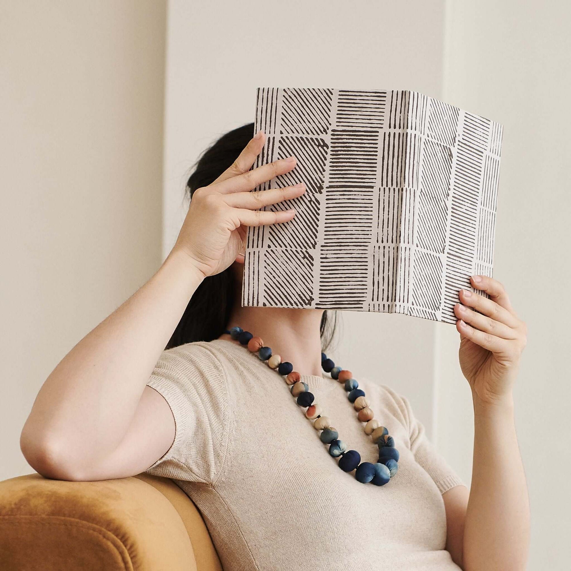 Woman wearing a Mihika silk beaded necklace while holding an art print, showcasing the necklace's vibrant colors and craftsmanship.
