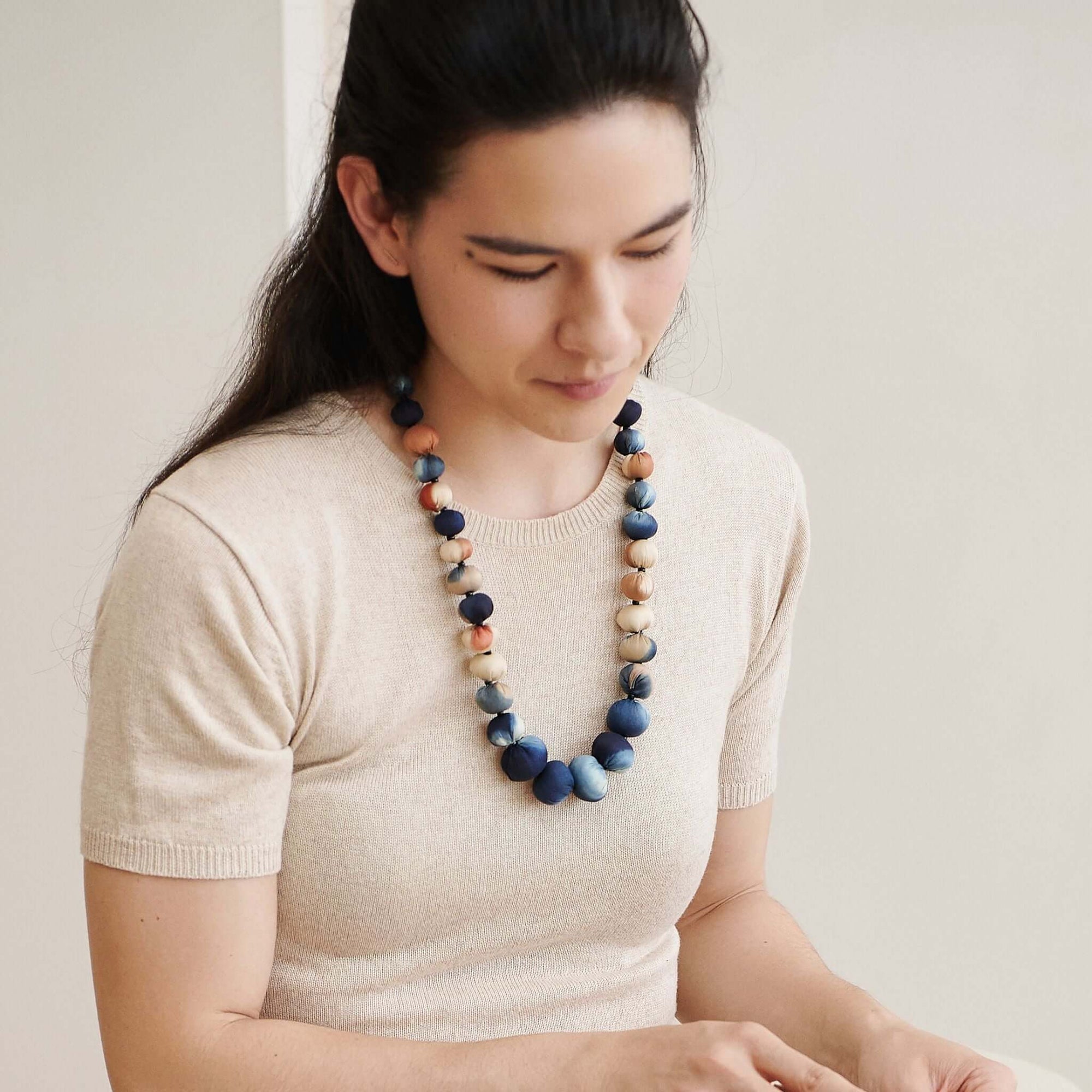 Mihika silk beaded necklace worn by a woman, showcasing handcrafted beads in soft colors, reflecting artisanal beauty.