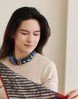 Mihika silk beaded necklace worn by a woman holding a patterned scarf, showcasing modern artisanal design.