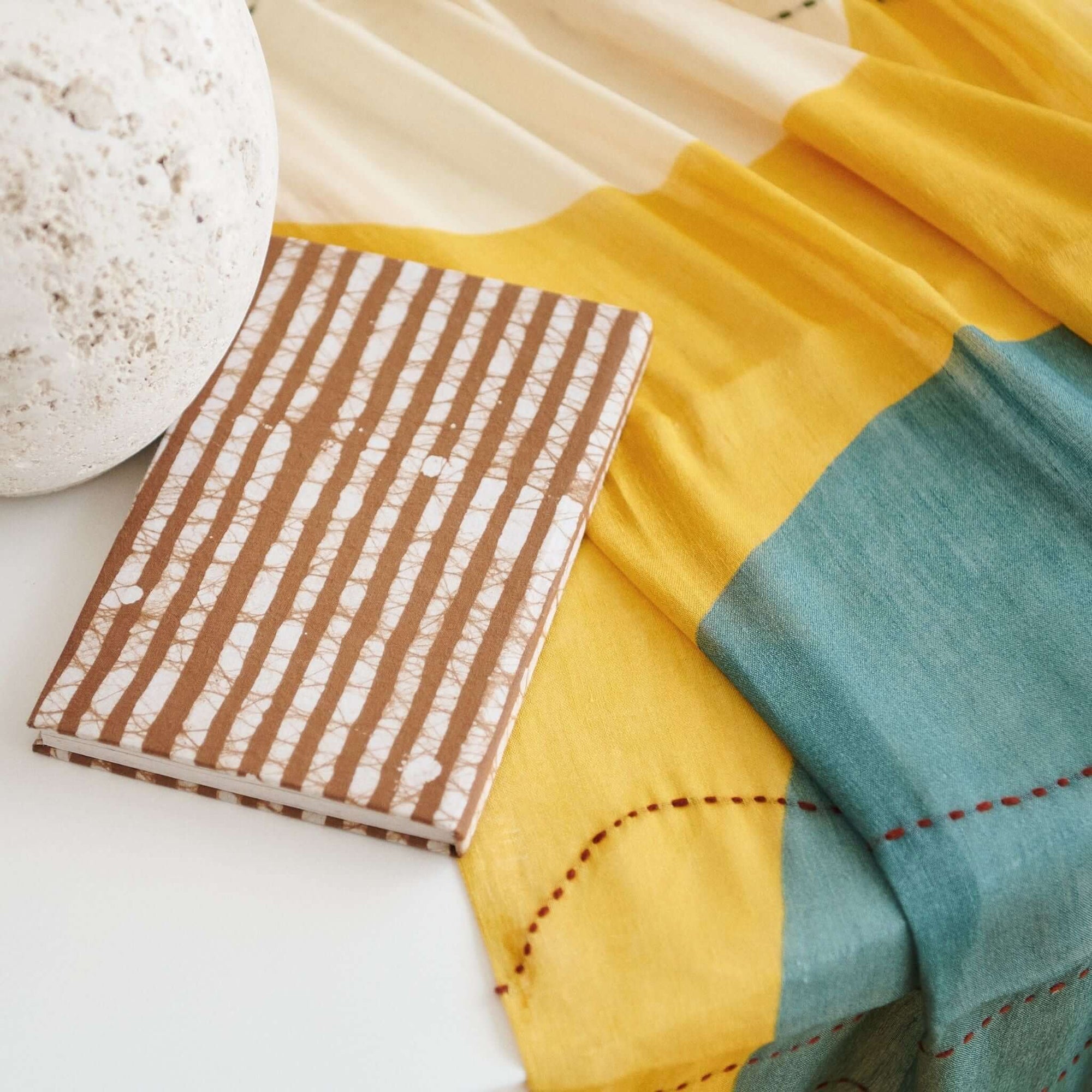 Oak Brown Zero Waste Handmade Artisanal Journal on a colorful fabric backdrop with a stone decoration.