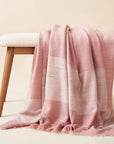 Rosa Plush Maroon Plush Merino Queen Bedspread / Large Throw displayed on a wooden bench in soft pink hues.