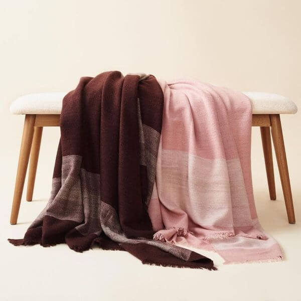 Rosa Plush Maroon Plush Merino Queen Bedspread / Large Throw draped elegantly on a bench, showcasing its luxurious design.