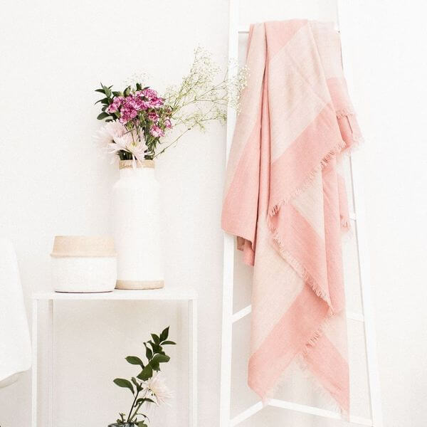 Rosa Plush Maroon Plush Merino Queen Bedspread / Large Throw displayed on a stand with flowers and decor in a modern setting.