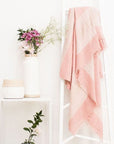 Rosa Plush Maroon Plush Merino Queen Bedspread / Large Throw displayed on a stand with flowers and decor in a modern setting.