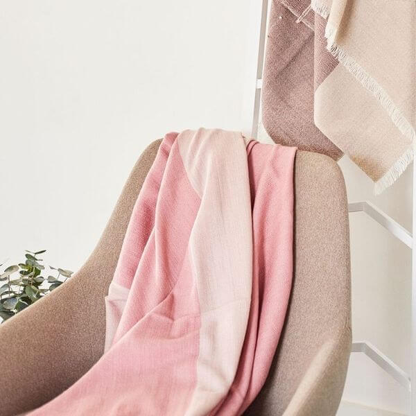 Rosa Plush Maroon Plush Merino Queen Bedspread / Large Throw draped over a stylish chair, showcasing its luxurious texture.