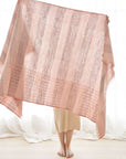 Silica Rose In Shades of Salmon Pink Gray Stripes Pattern Soft Handwoven Merino Throw displayed by a person.