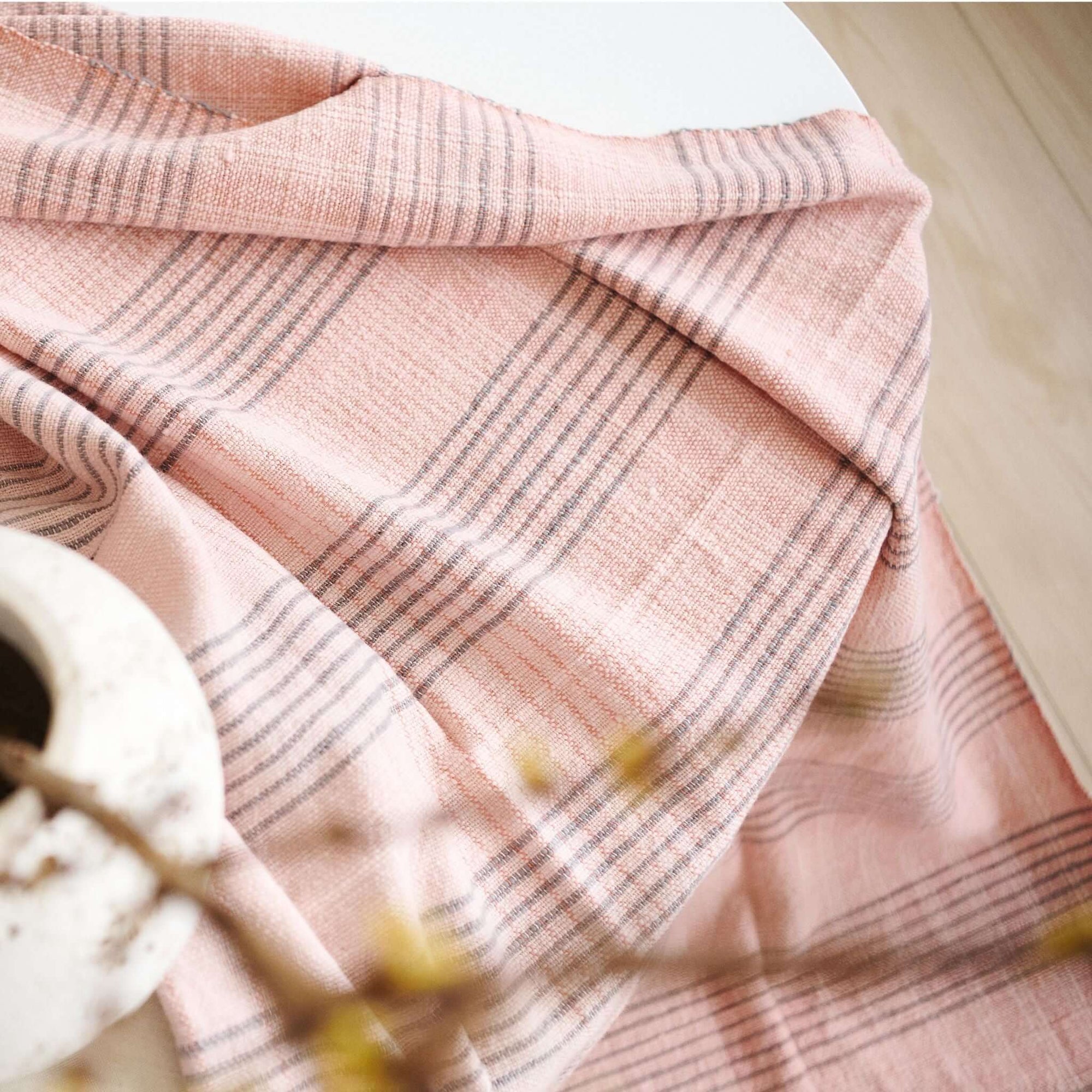 Silica Rose In Shades of Salmon Pink Gray Stripes Pattern Soft Handwoven Merino Throw draped over a table.