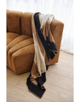 Siro Brown Handwoven Merino Artisan Throw Blanket draped over a modern couch, showcasing its elegant design and colors.