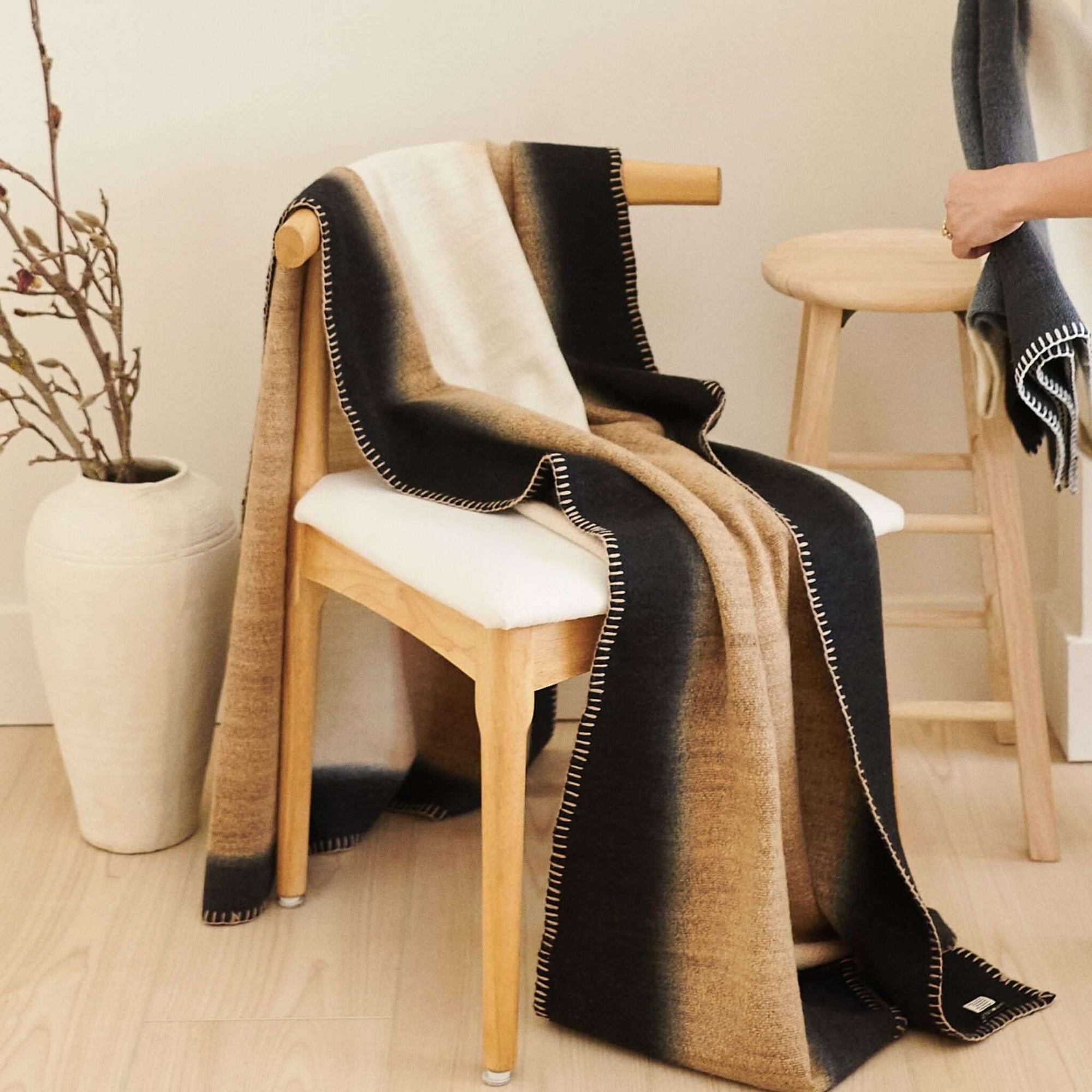 Siro Brown Handwoven Merino Artisan Throw Blanket draped over a wooden chair, showcasing its texture and design.