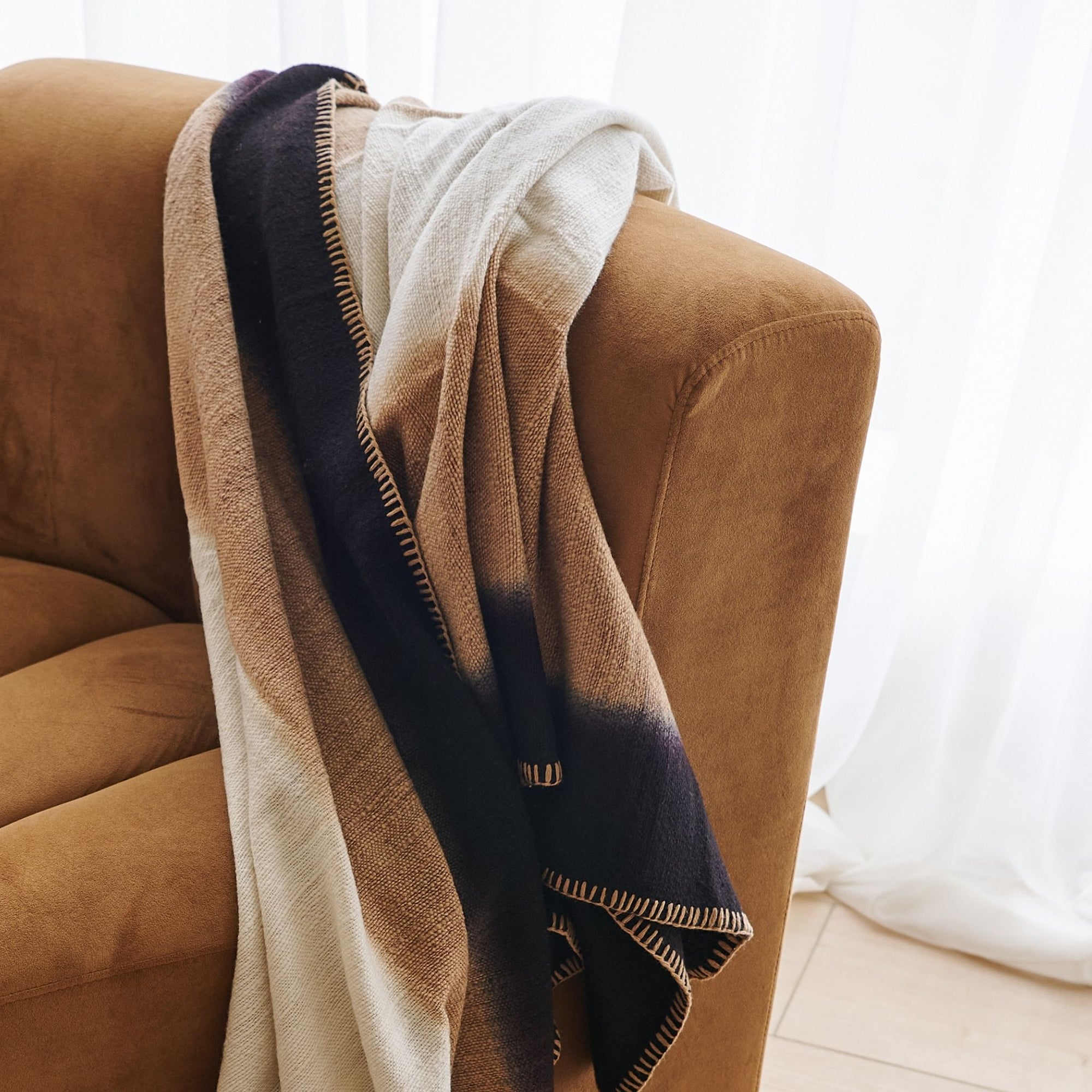 Siro Brown Handwoven Merino Artisan Throw Blanket draped over a cozy sofa, showcasing its soft textures and elegant design.