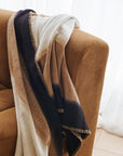 Siro Brown Handwoven Merino Artisan Throw Blanket draped over a cozy sofa, showcasing its soft textures and elegant design.