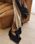 Siro Brown Handwoven Merino Artisan Throw Blanket draped over a cozy sofa, showcasing its texture and craftsmanship.