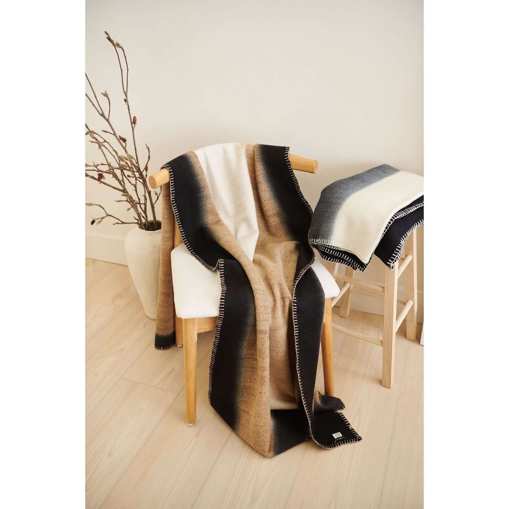 Siro Brown Handwoven Merino Artisan Throw Blanket draped over a wooden chair, showcasing soft textures and warm colors.