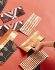 Tisa Artisanal Pouch In Black Pink Triangle Print arranged on a colorful surface.