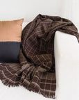 Treacle Checks Pattern Organic Cotton Handloom Throw draped over a couch with a decorative pillow.