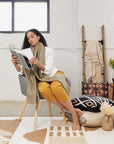 Dyoon Abstract Pattern Handwoven Artisanal Wool Rug featured in cozy living space with model reading a magazine.